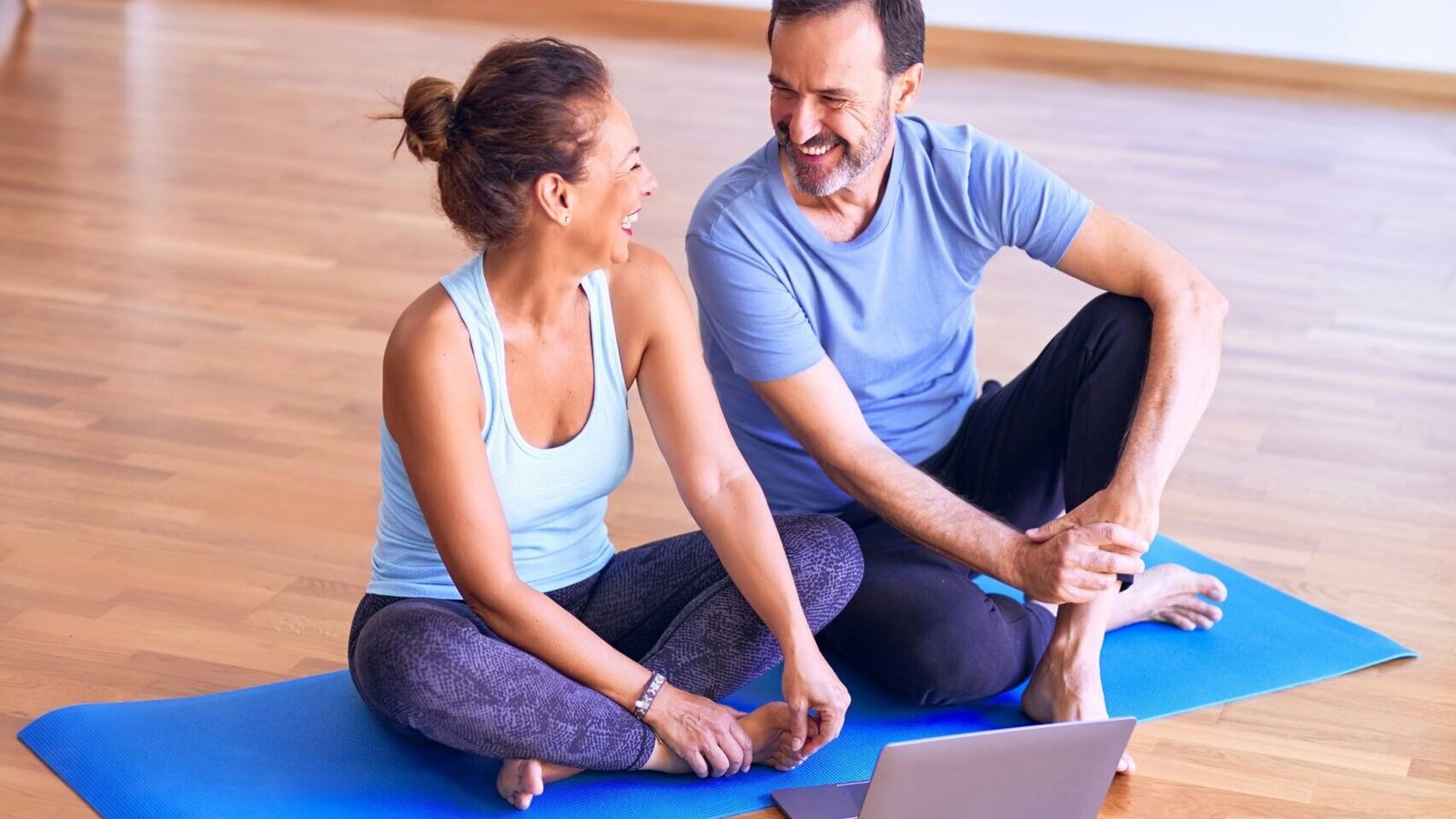 man in white tank top and gray pants sitting on blue yoga mat